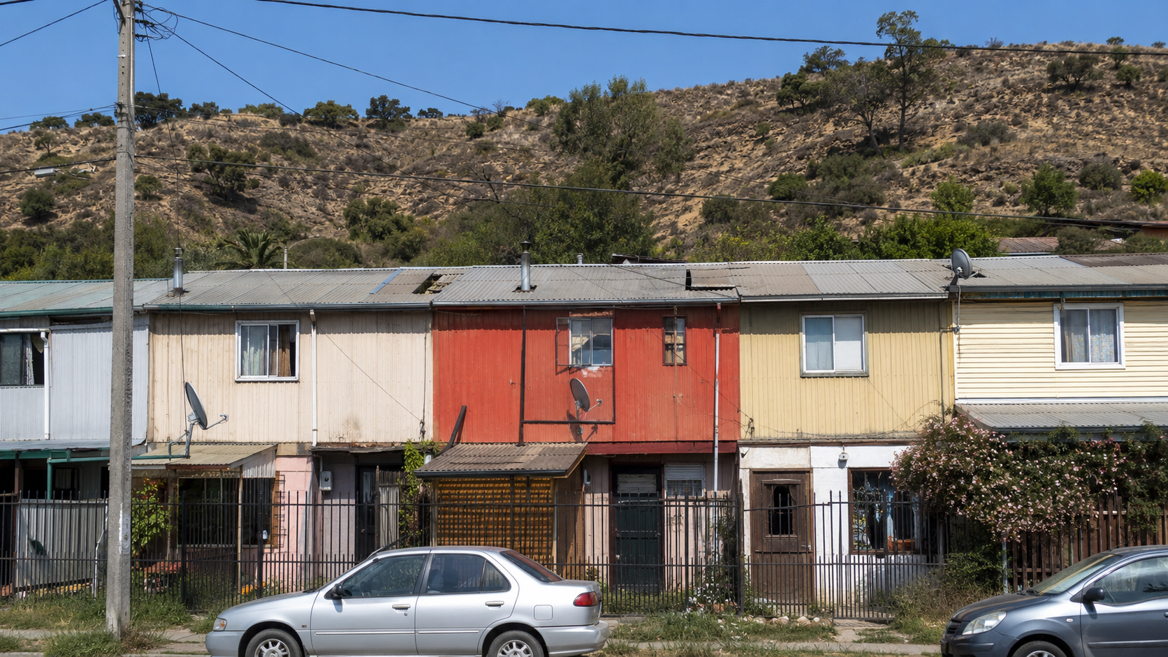 Casas pareadas en sector de interfaz urbano-forestal chileno con cerro y vegetación seca visible al fondo